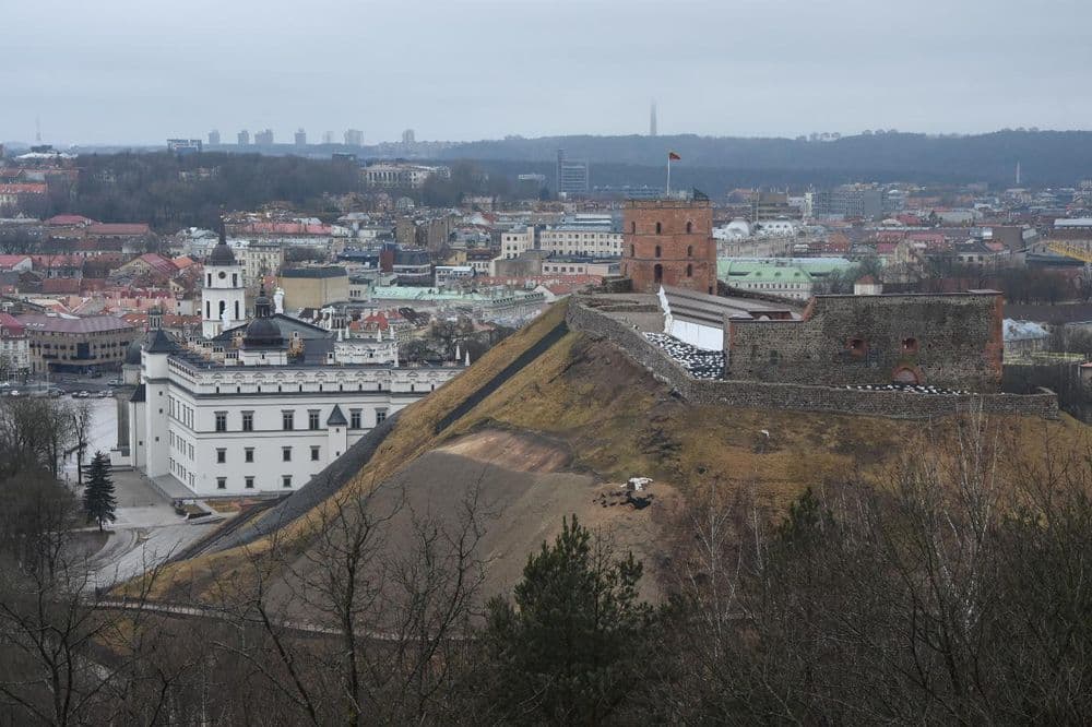 Tour en briques sur une colline verte au-dessus de la vieille ville, un palais blanc au premier plan